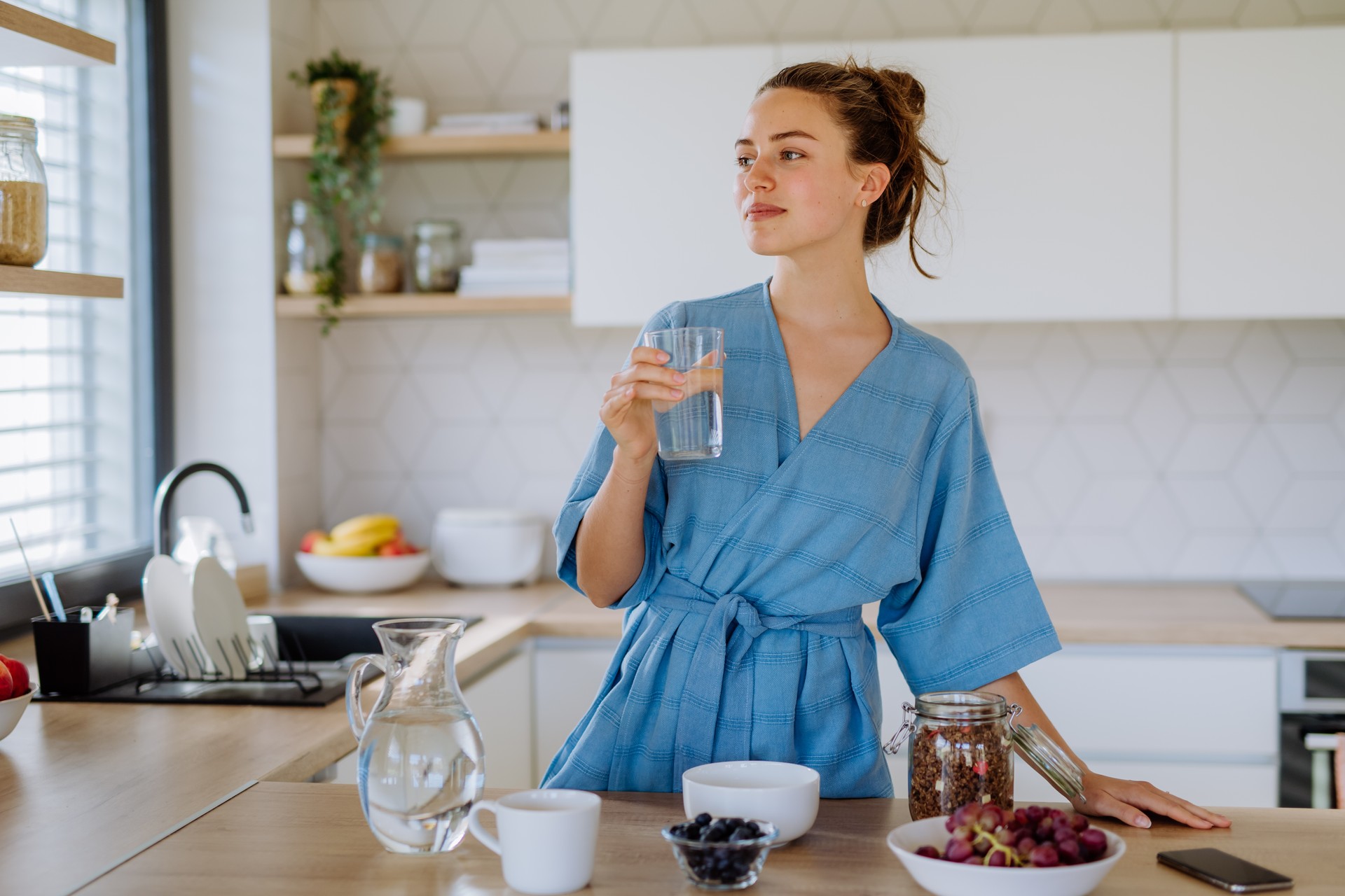 Young woman preparing muesli for breakfast in her kitchen, morning routine and healthy lifestyle concept.